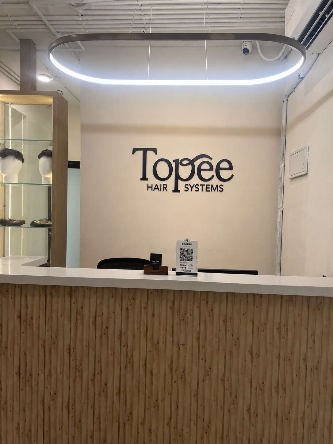 Lit glass cabinets displaying men's hair systems and women's hair toppers at the Topee studio