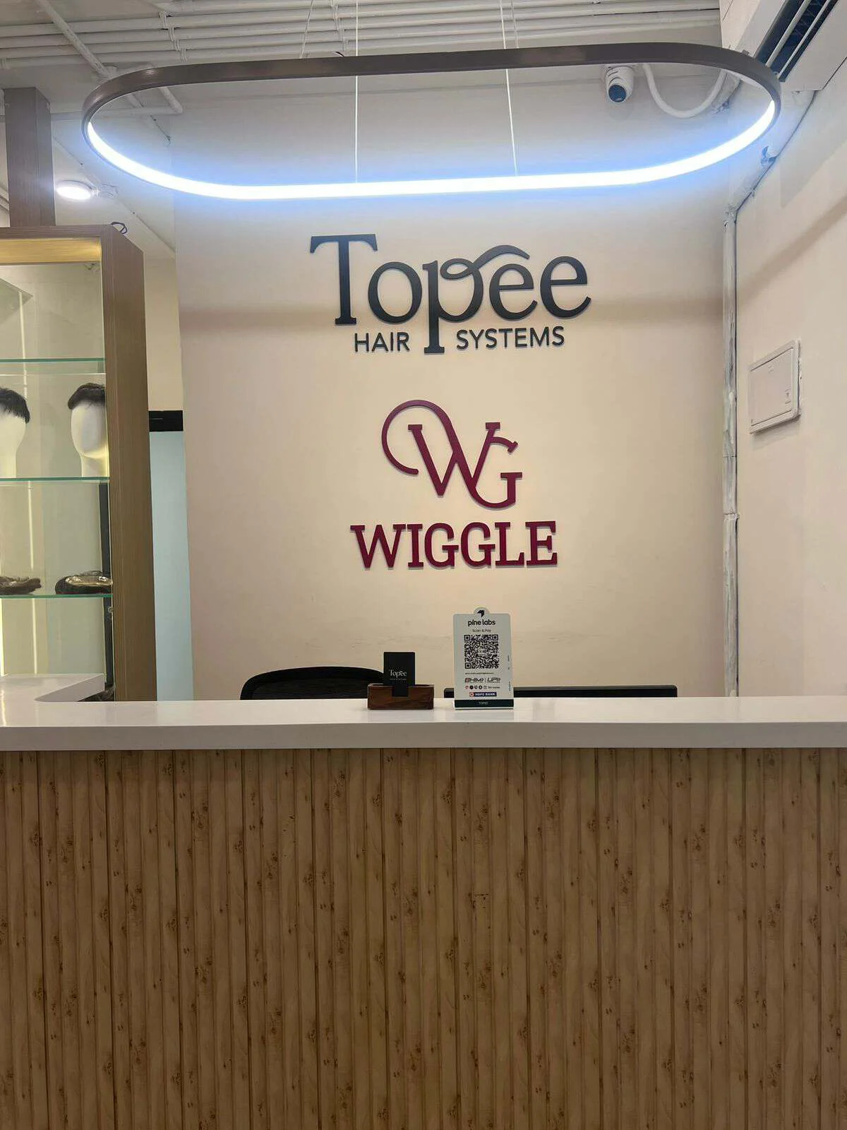 Lit glass cabinets displaying men's hair systems and women's hair toppers at the Topee studio