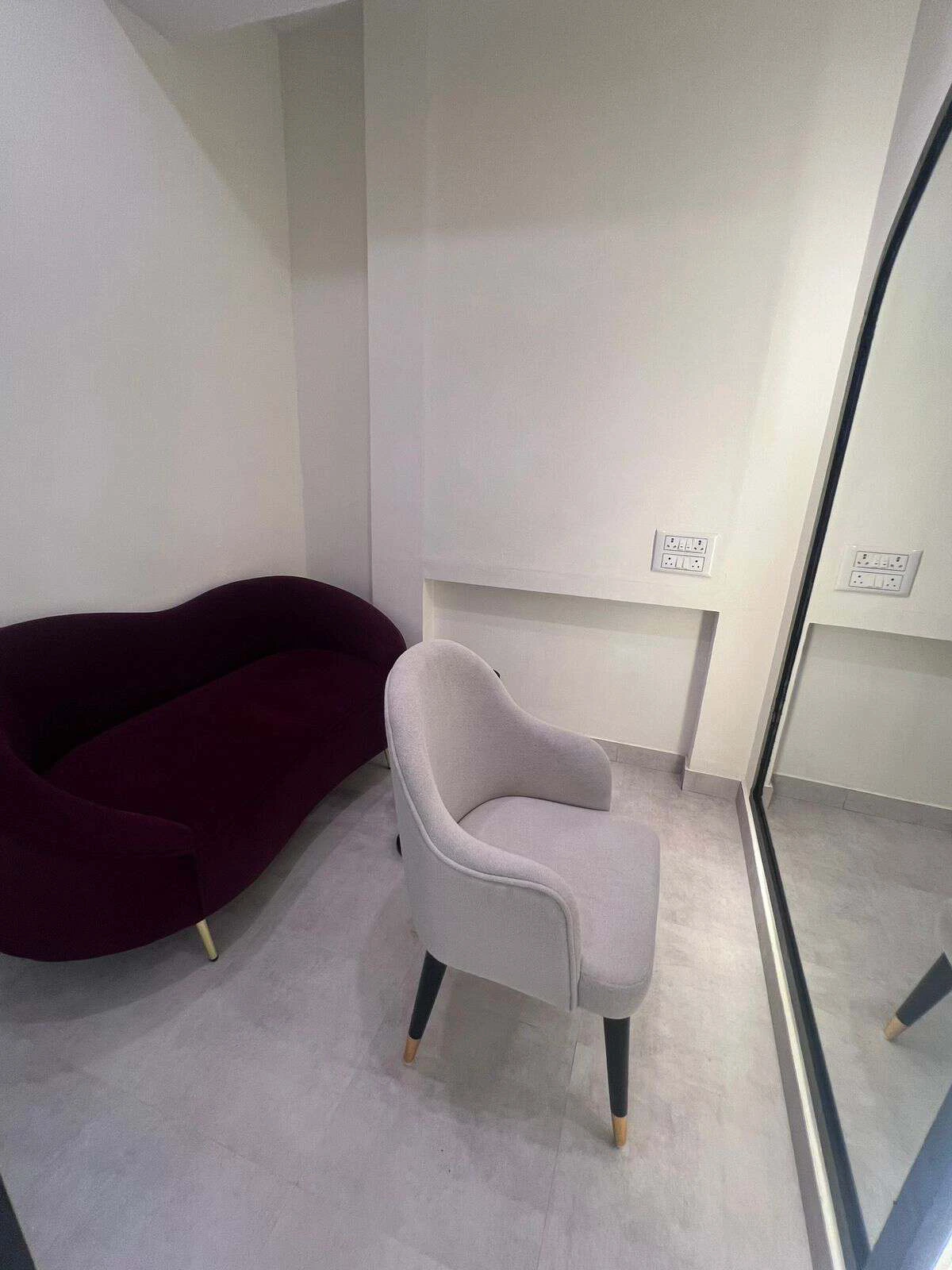 A private waiting lounge at the Topee studio with a burgundy sofa, armchair and full-length mirror